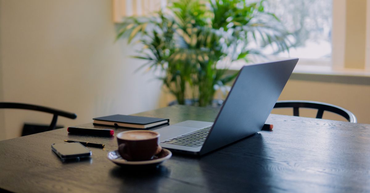 Laptop and coffee on a table, workspace cover for Quo digital staff case study